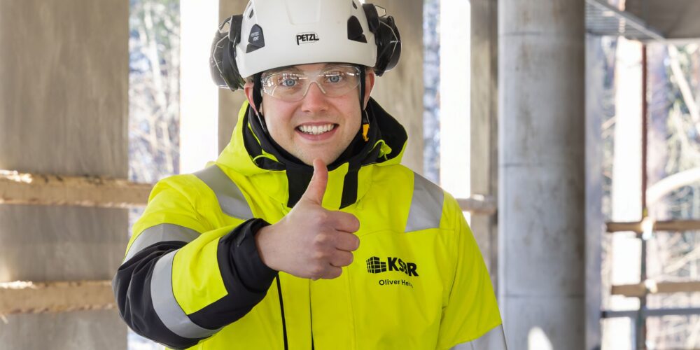 Työntekijä näyttää peukkua turvaliiveissään.