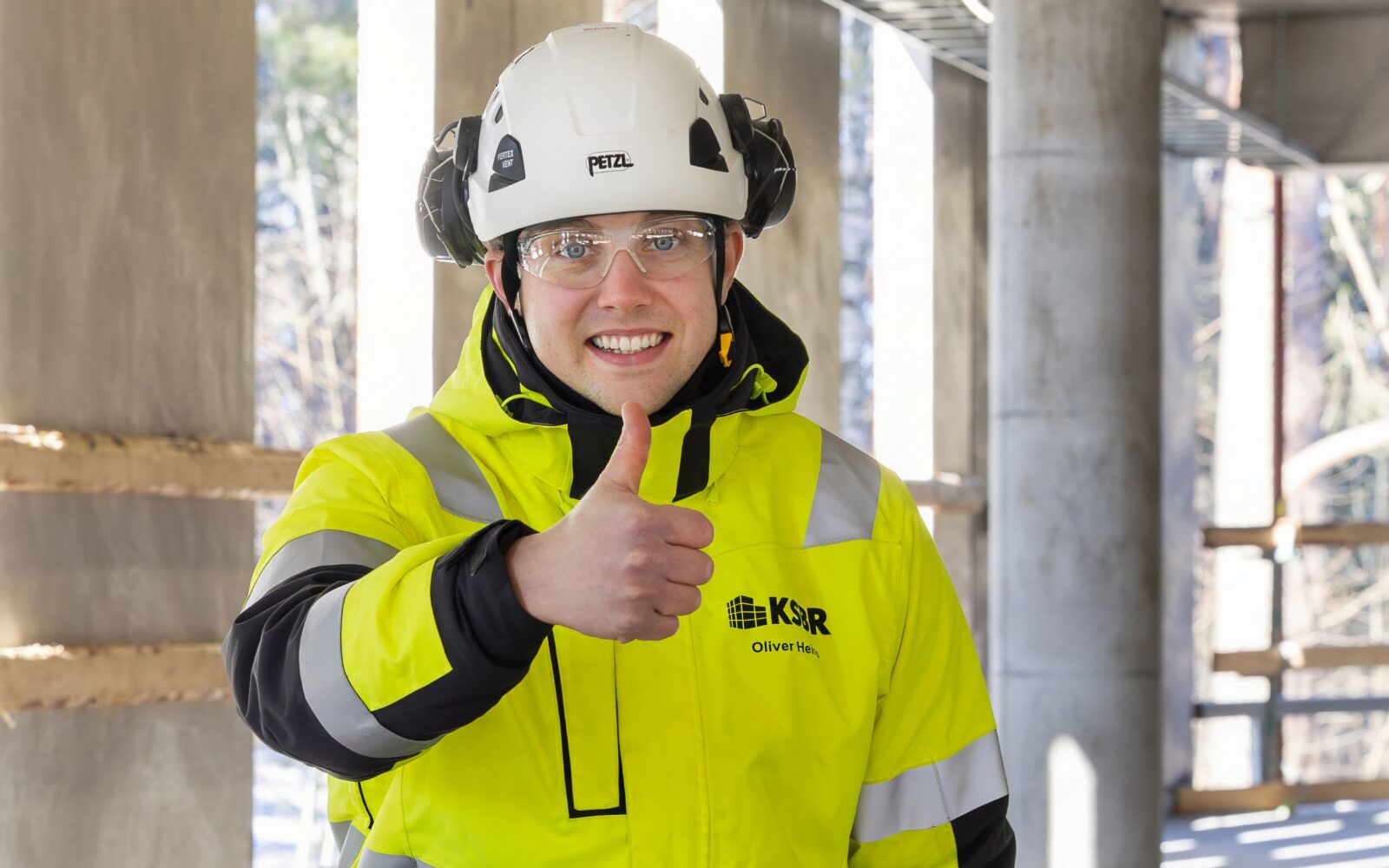 Työntekijä näyttää peukkua turvaliiveissään.