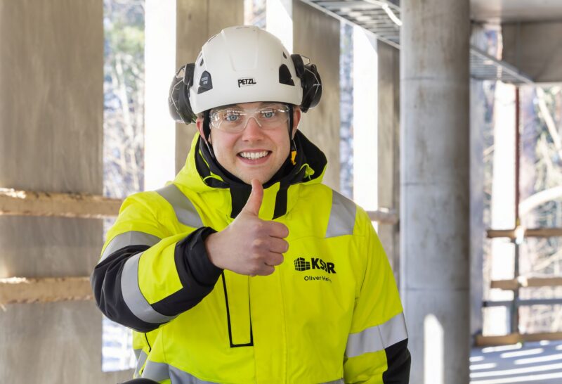 Työntekijä näyttää peukkua turvaliiveissään.