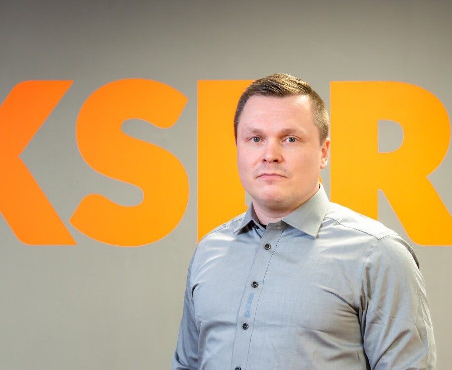 Toimitusjohtaja seisoo KSBR:n logoseinän edessä.